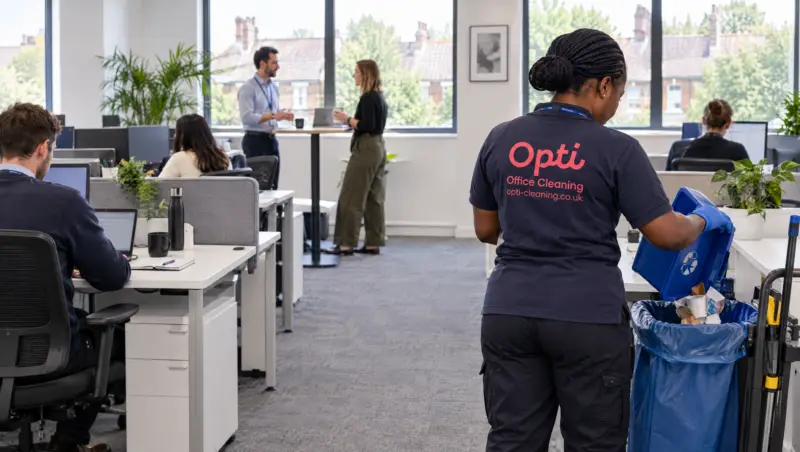 An Opti Clean operative emptying a recycling bin in a working office